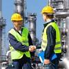 Two men in yellow safety vests and hard hats shaking hands at a chemical facility.