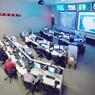 NICC information sharing control room Picture of the NICC information sharing control room with rows of desks with computers and large TV screens on one wall.