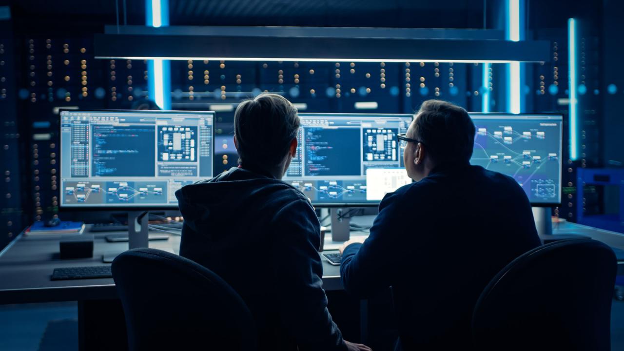 Two employees sitting at computer monitors. 