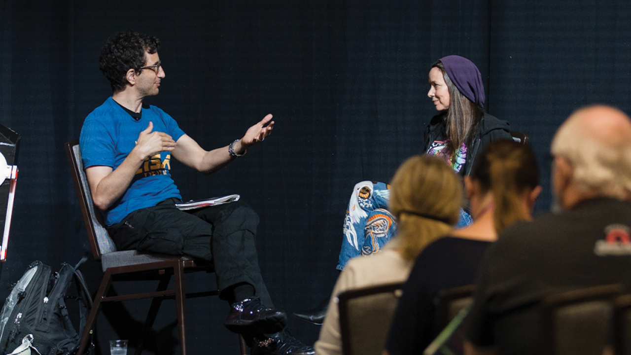 Two people on stage talking at a conference