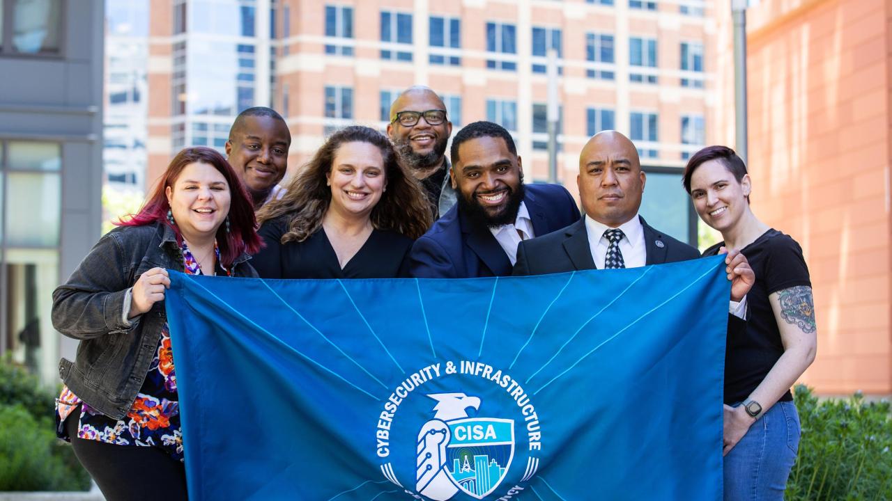 Employees at CISA holding the CISA flag