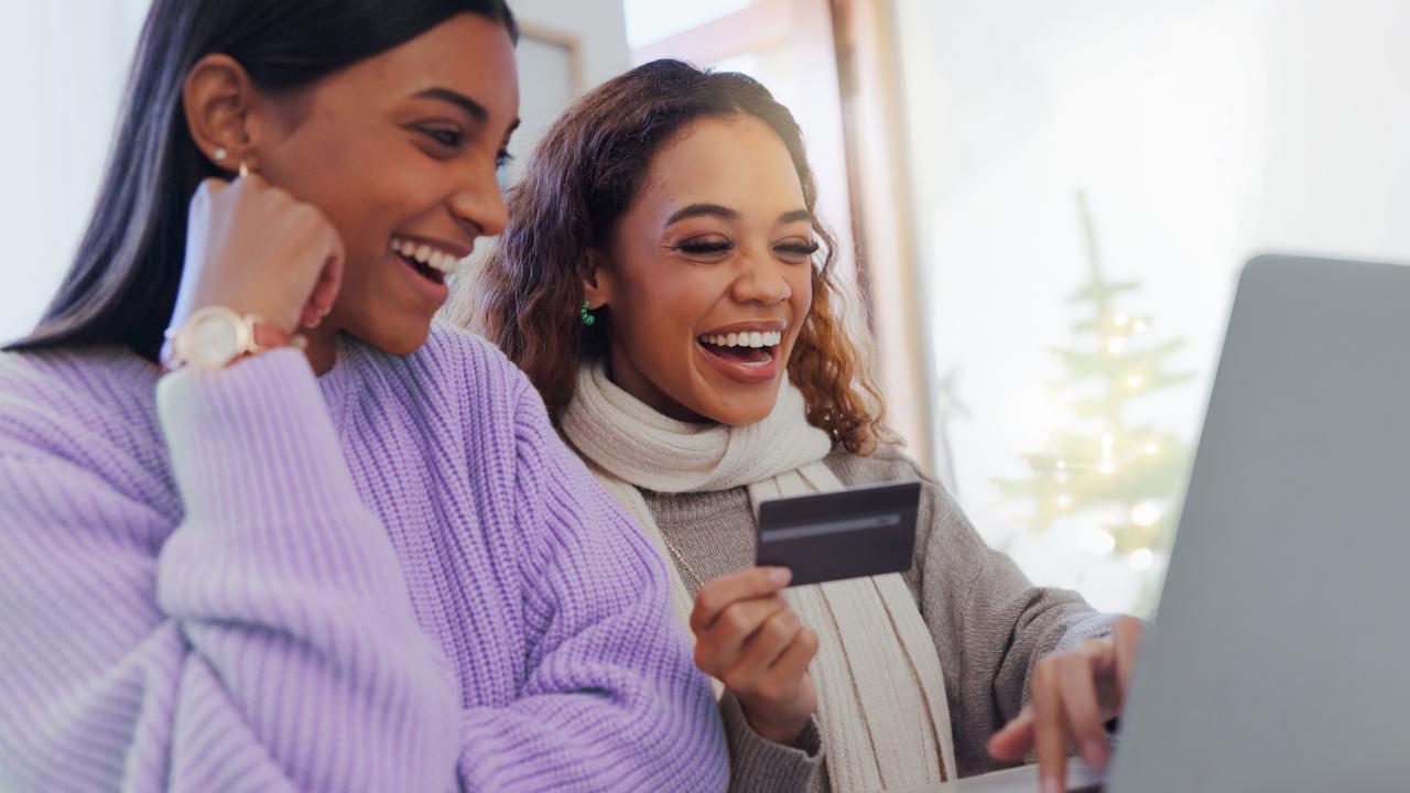two women shop online in front of a computer