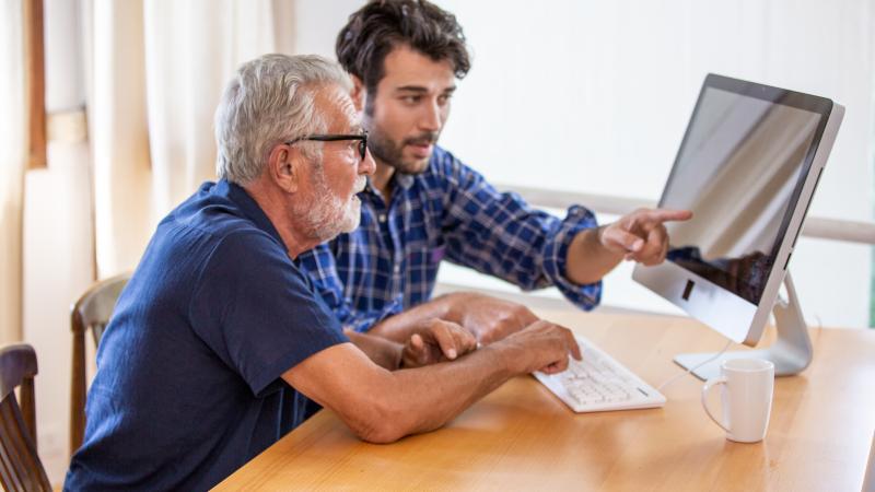 Man showing elderly man how to use the computer