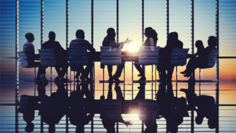 Silhouette of group of people around a table having a business meeting