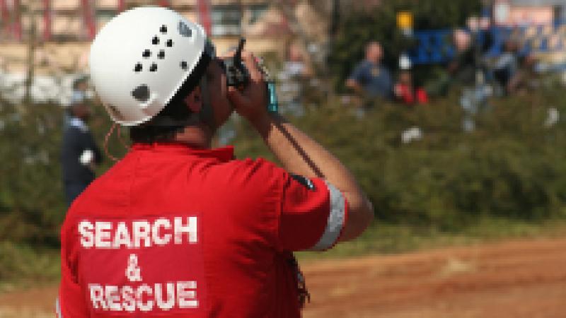 Search and Rescue employee looking at the sky speaking into a walkie talkie