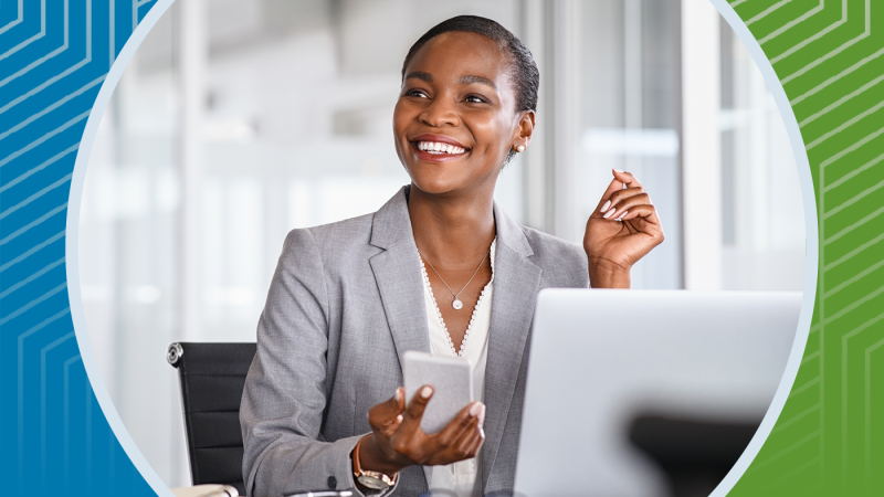 woman smiling at her desk holding a phone