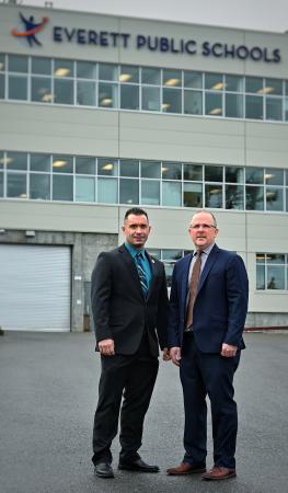 Two members of CISA Region 10 in front of an Everett Public Schools building.