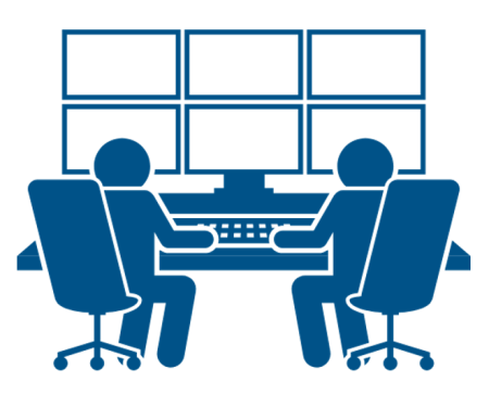 2 individuals sitting at a desk viewing multiple computer monitors. 