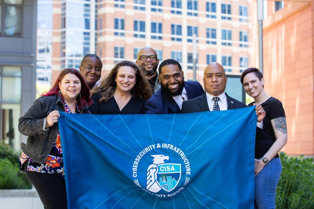 Employees at CISA holding the CISA flag