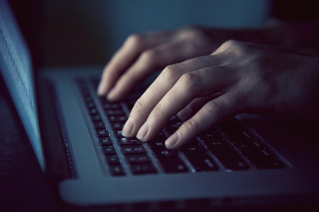 Woman's hands typing on laptop in the dark