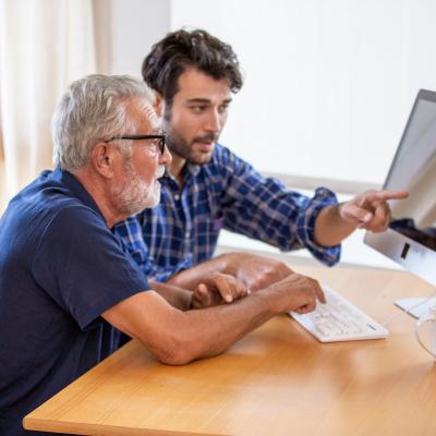 Man showing elderly man how to use the computer